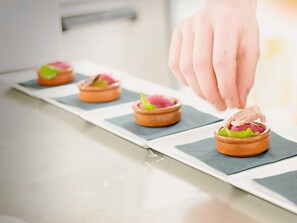 A series of terracotta dishes with food garnishes on a white countertop. - Logis Hôtel de France Restaurant le Lucullus (Montmorillon)