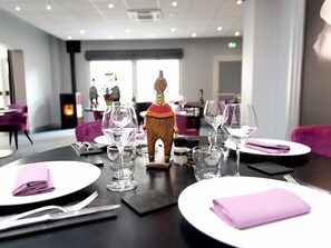 A dining table set with wine glasses, plates, and a decorative wooden figure. - Logis Hôtel de France Restaurant le Lucullus (Montmorillon)
