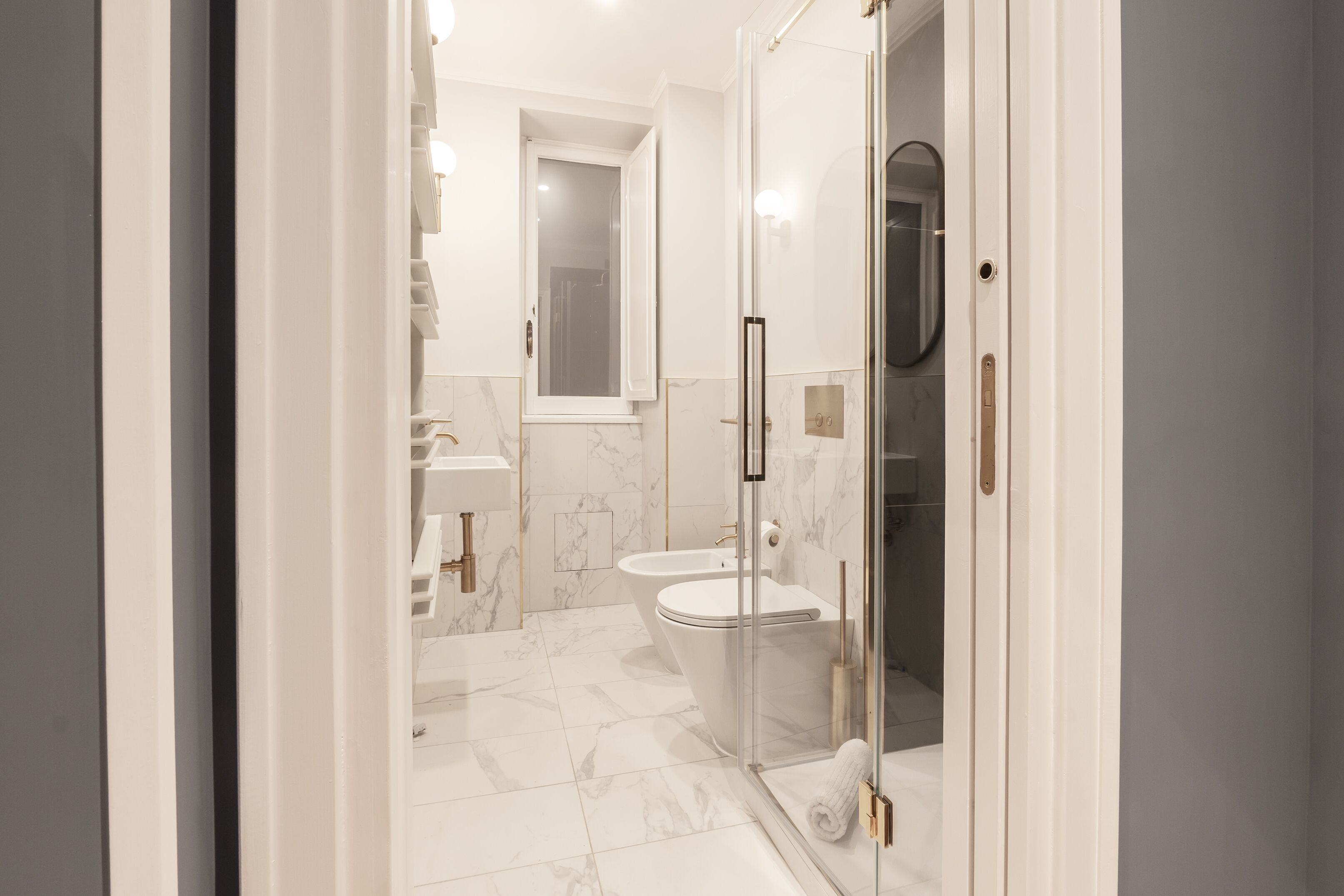 A modern bathroom with a glass shower enclosure, a white toilet, and a marble-tiled floor.