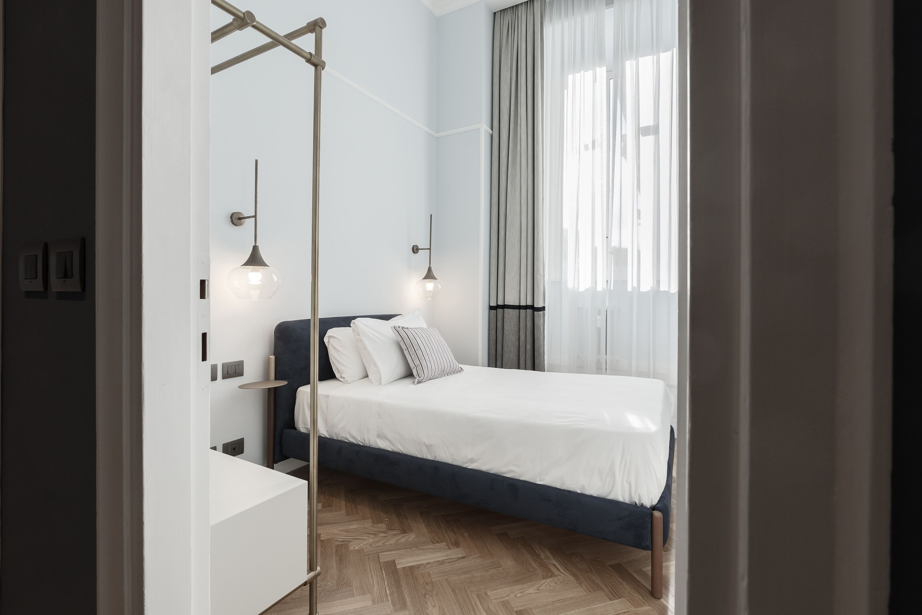 A modern bedroom with a bed, bedside tables, and a hanging light fixture.