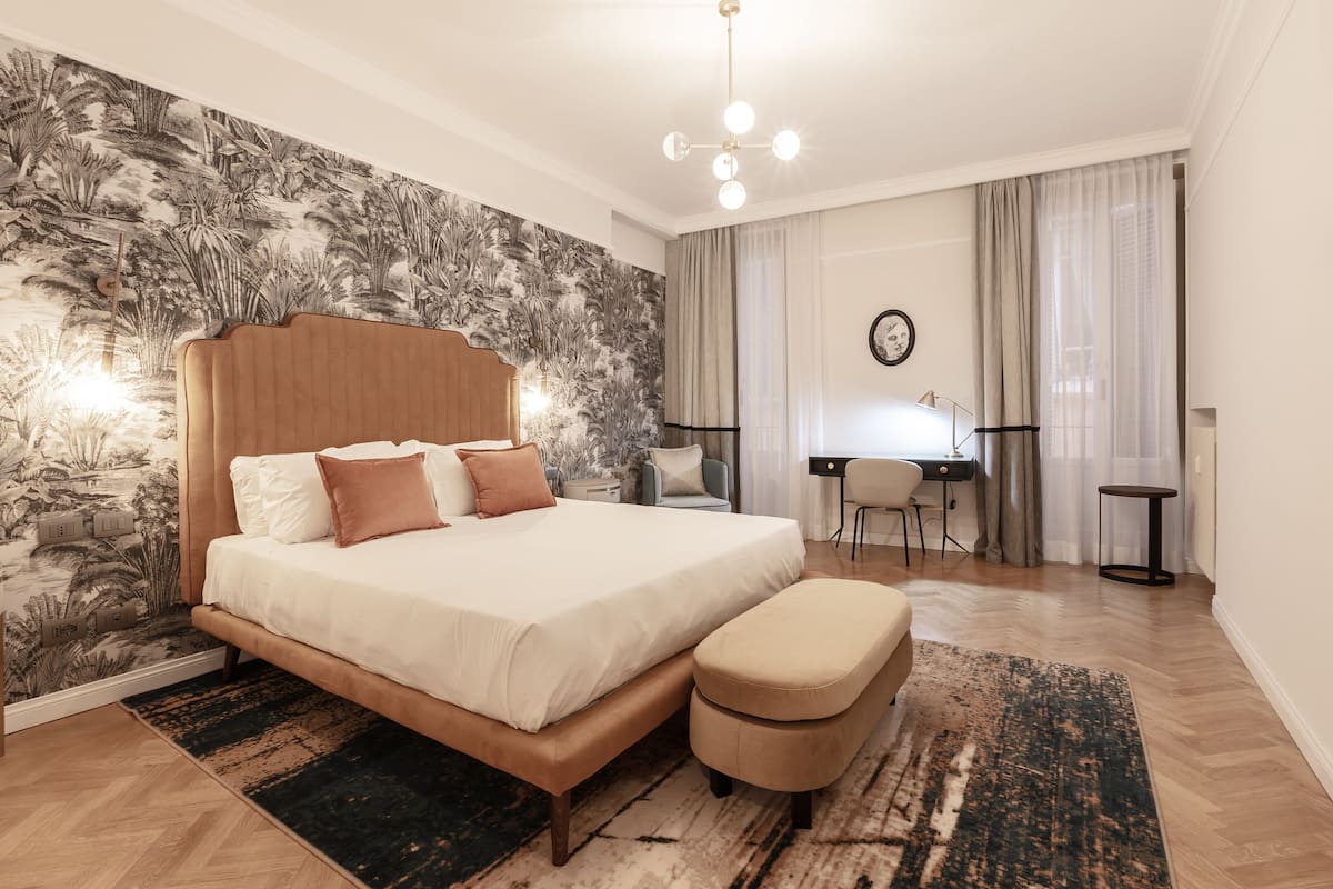 A bedroom with a large bed, a desk, and a chair.