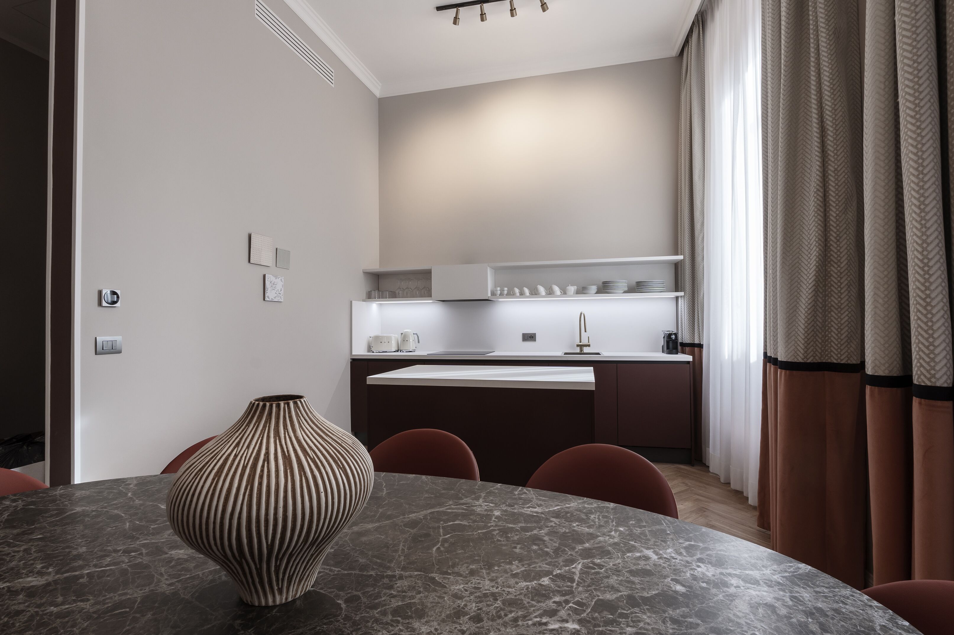 A modern kitchen with a marble countertop, a built-in oven, and a white backsplash.
