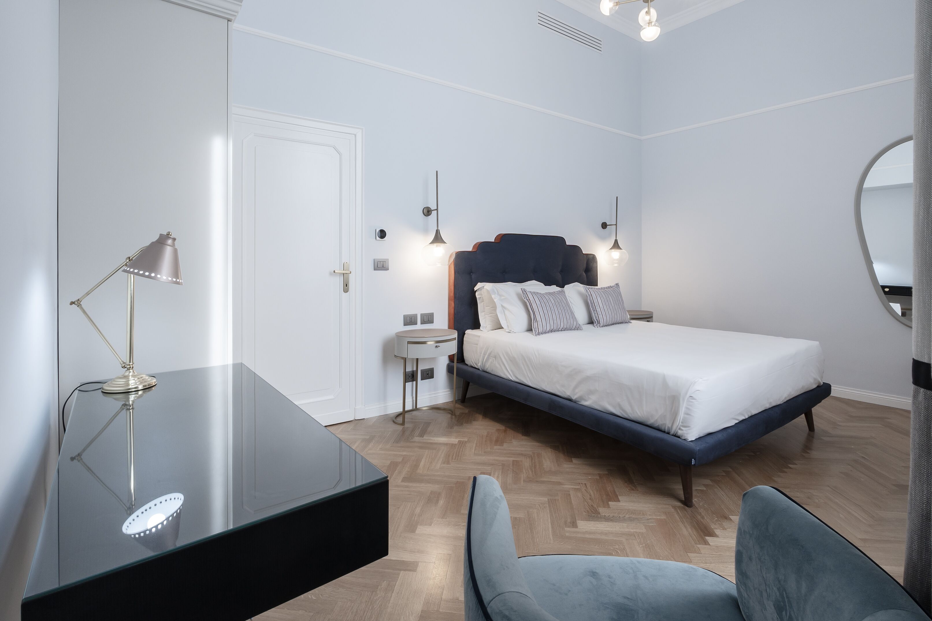 Quarto moderno com cama, mesas de cabeceira, escrivaninha e uma cadeira.