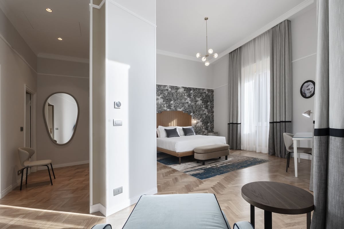 A modern bedroom with a bed, bedside table, and a large mirror.