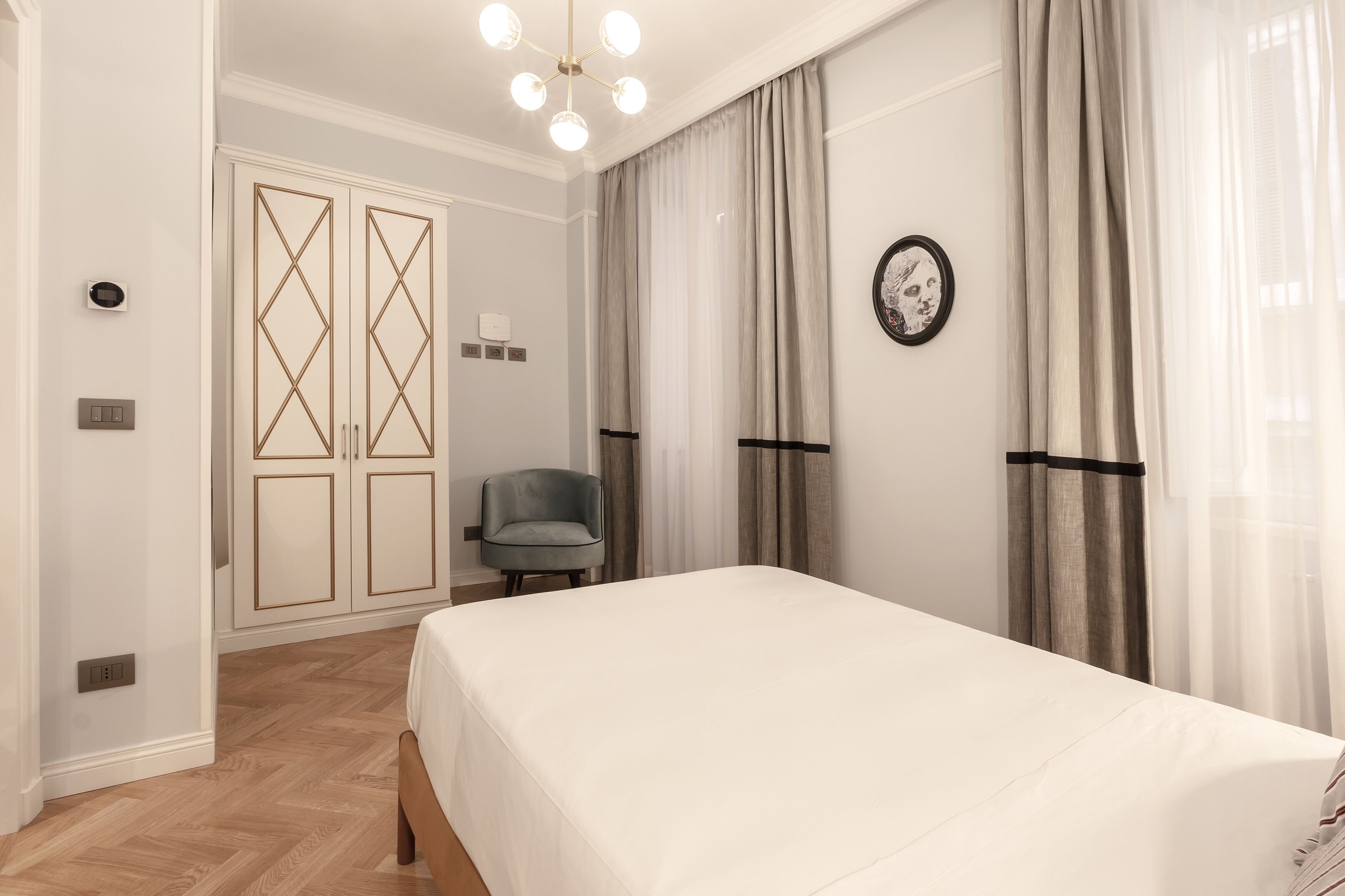 Quarto com cama, cadeira, guarda-roupa e lustre.