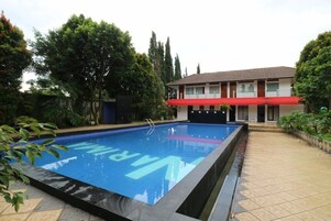 Una piscina con toldo rojo y un edificio de techo rojo al fondo.