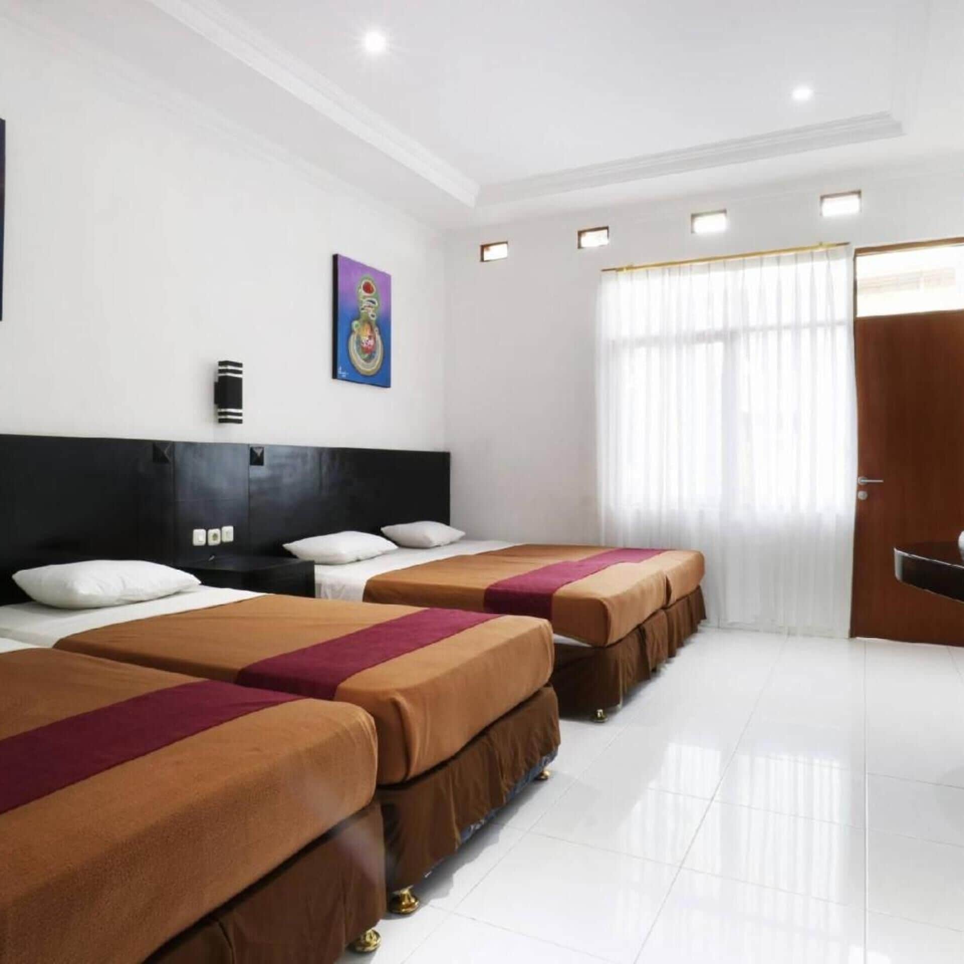 A hotel room with two beds, a large window with curtains, and a painting on the wall.
