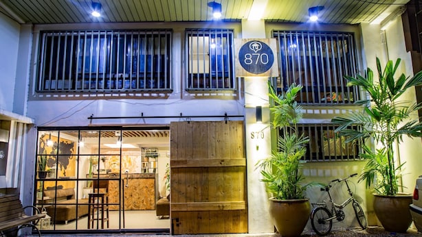 Un bâtiment avec une façade en bois, une grande plante en pot et un vélo garé à l’extérieur.