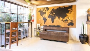 Un intérieur moderne avec une grande carte du monde accrochée au mur, un canapé marron, une chaise en bois et une table en verre avec des chaises.