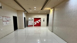 A clean, well-lit hallway with tiled floors, a red elevator door, and informational posters on the walls. - Super OYO 144 Al Tawasi Furnished Apartments (Salalah)