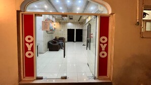 A hotel entrance with a red and white sign, a reception desk, and a seating area with two sofas. - Super OYO 144 Al Tawasi Furnished Apartments (Salalah)