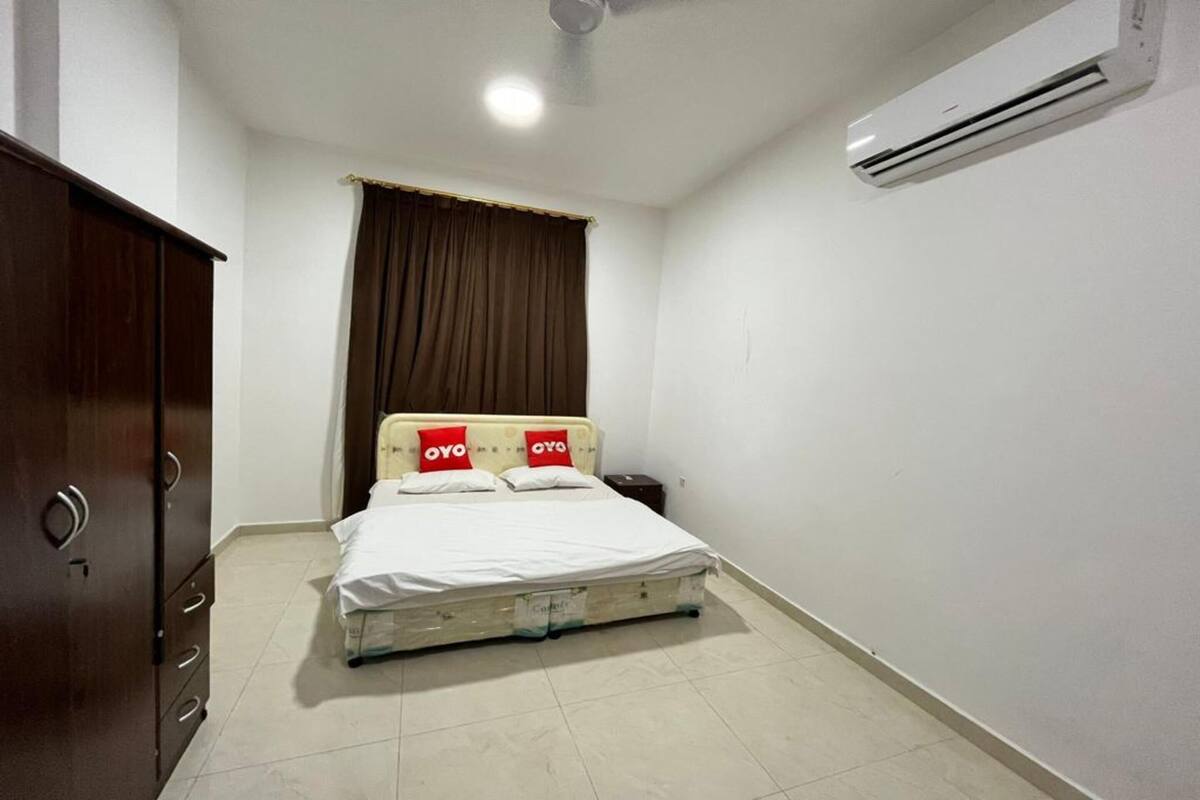 A bedroom with a bed, a wardrobe, an air conditioner, and a ceiling fan.