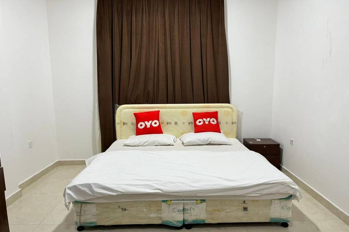 A small, clean room with a bed, a nightstand, and a curtain.