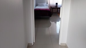 A narrow hallway leading to a bedroom with a bed, a nightstand, and a window with curtains. - Special Inn Bed and Breakfast  (Windhoek)