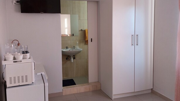 A bedroom with a bed, a TV, a wardrobe, and a kitchenette area. - Special Inn Bed and Breakfast  (Windhoek)