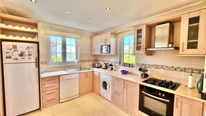 A modern kitchen with a dishwasher, washing machine, microwave, stove, and a sink. - Private Villa ErzanMyne Private Pool Mountain View Ovacik Oludeniz (Muğla)