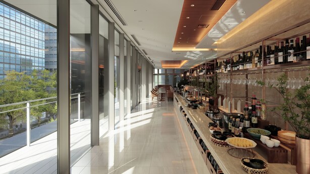 Un bar moderne avec un long comptoir, de grandes fenêtres et une vue sur la ville.