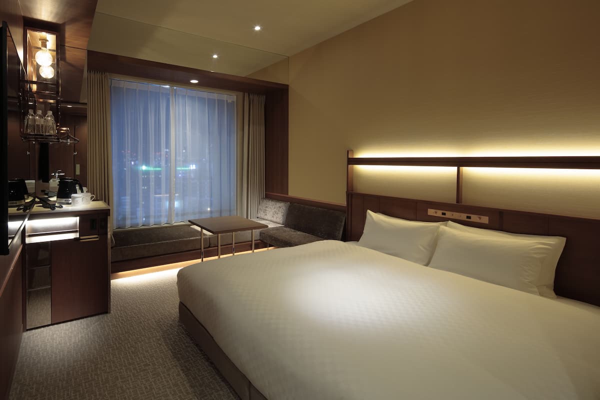 Una habitación de hotel con una cama grande, un escritorio con silla, una mesita y un sofá.