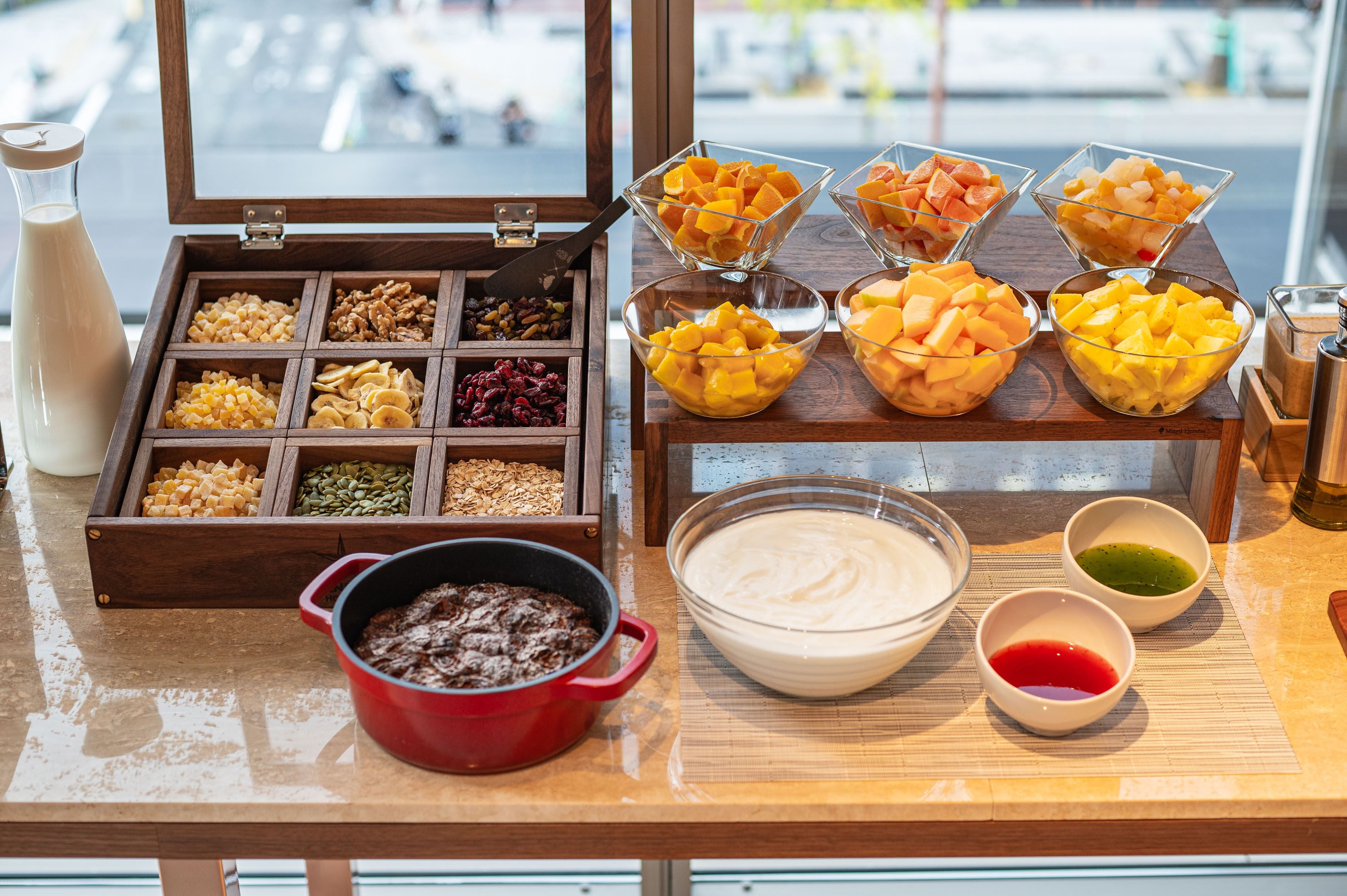 A breakfast buffet with various fruits, nuts, and a bowl of yogurt.