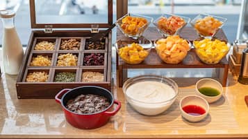 A breakfast buffet with various fruits, nuts, and a bowl of yogurt.