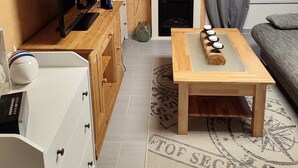Un salon moderne avec une télévision, des meubles en bois, une cheminée et un canapé gris.