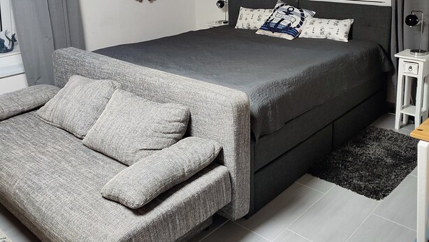 Une chambre à coucher avec un lit, un canapé, un miroir, une horloge et une petite table.