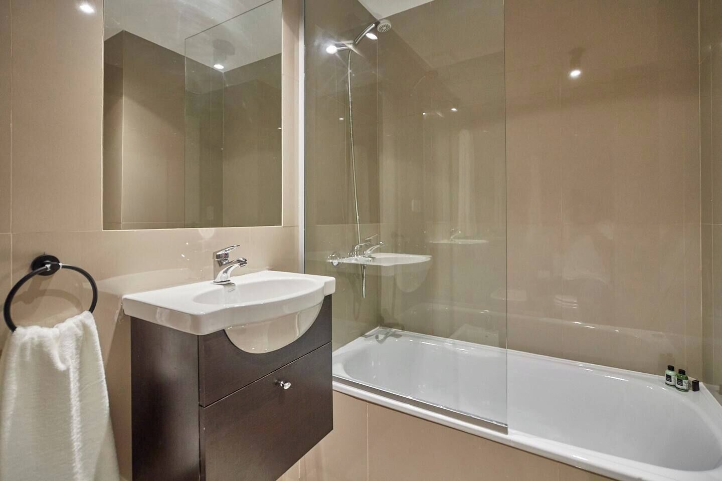 A modern bathroom with a glass-enclosed shower, a vanity with a sink, and a bathtub.
