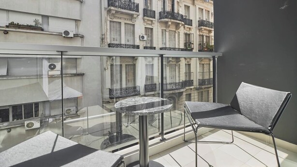 A balcony with a glass railing, a round table, and two chairs. - NoMa Work & Travel - 7A (Centro)