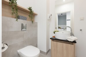 A modern bathroom with a toilet, sink, and shower.