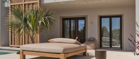 A modern poolside area with a lounge chair, a wooden pergola, and a clear pool.