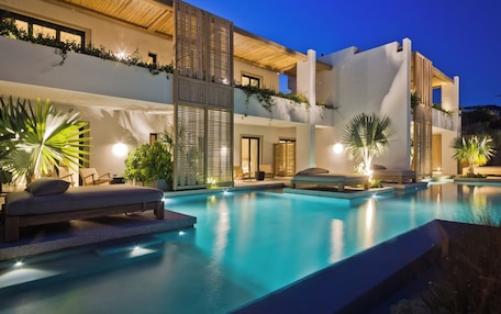 A modern hotel with a swimming pool, outdoor seating, and lush greenery.