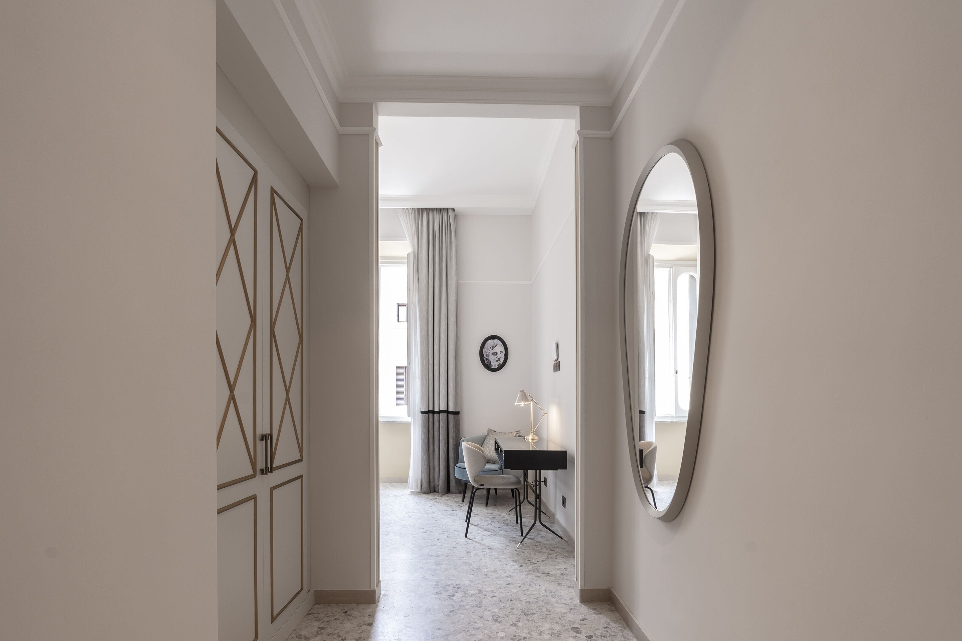 A hallway with a desk, chair, and a large mirror.