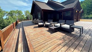 En træterrasse med udendørs siddepladser og en bygning med skråt tag.