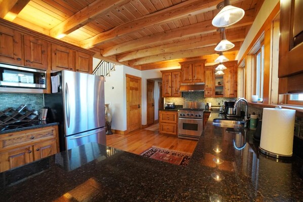 A spacious kitchen with wooden cabinets, granite countertops, stainless steel appliances, and a large island. - Luxurious Private Mountain Retreat w/Hot Tub + Sauna (Victor)