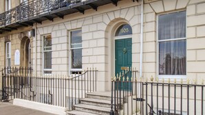 A building with a number '105' on the door, a green door, and a black wrought iron fence. - Sunbeach (Weymouth)