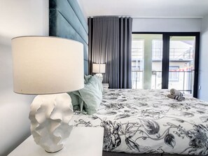 A hotel room with a bed, a white lamp, a window with curtains, and a view of buildings outside. - On the Wave by LovelyStay (Paúl do Mar)