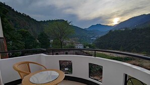 Ein Balkon mit Korbmöbeln und Blick auf ein Tal.