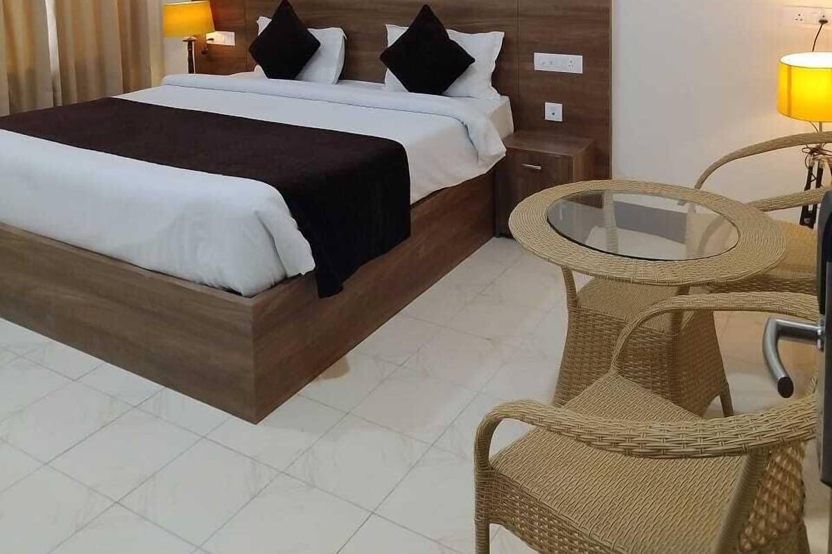 A hotel room with a wooden bed, two bedside lamps, a round wicker table, and a ceiling fan.