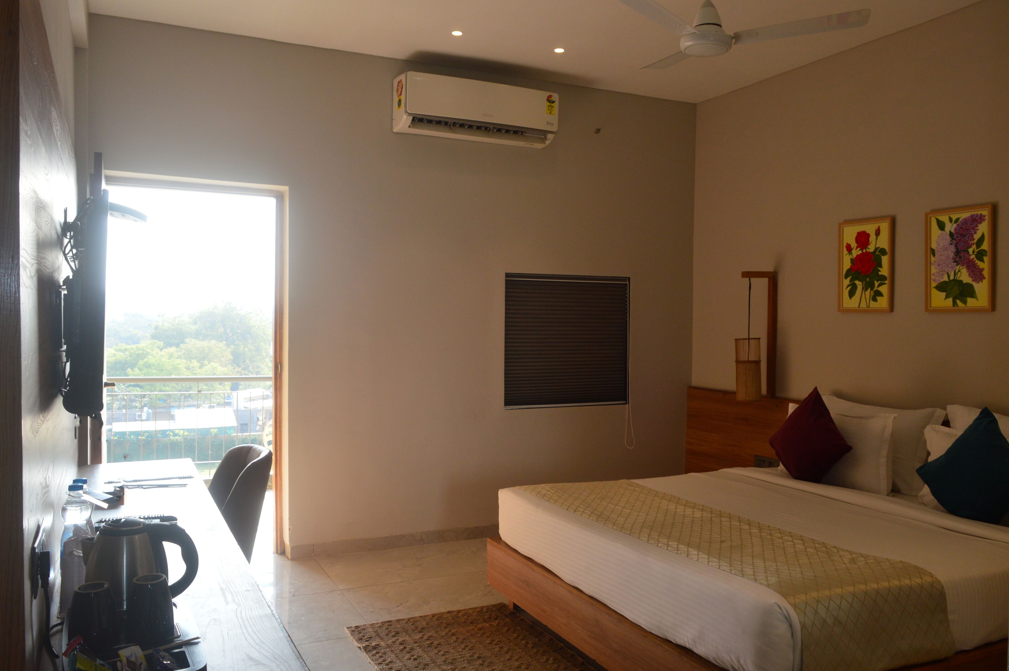 Un dormitorio con cama, ventana, aire acondicionado, ventilador de techo y vista a zonas verdes.