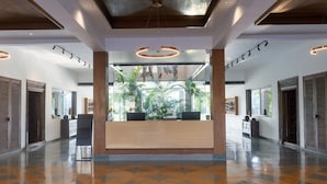 A spacious lobby with a reception desk, large windows, and a modern ceiling design. - Pathikashram Nilaya (Gandhinagar)