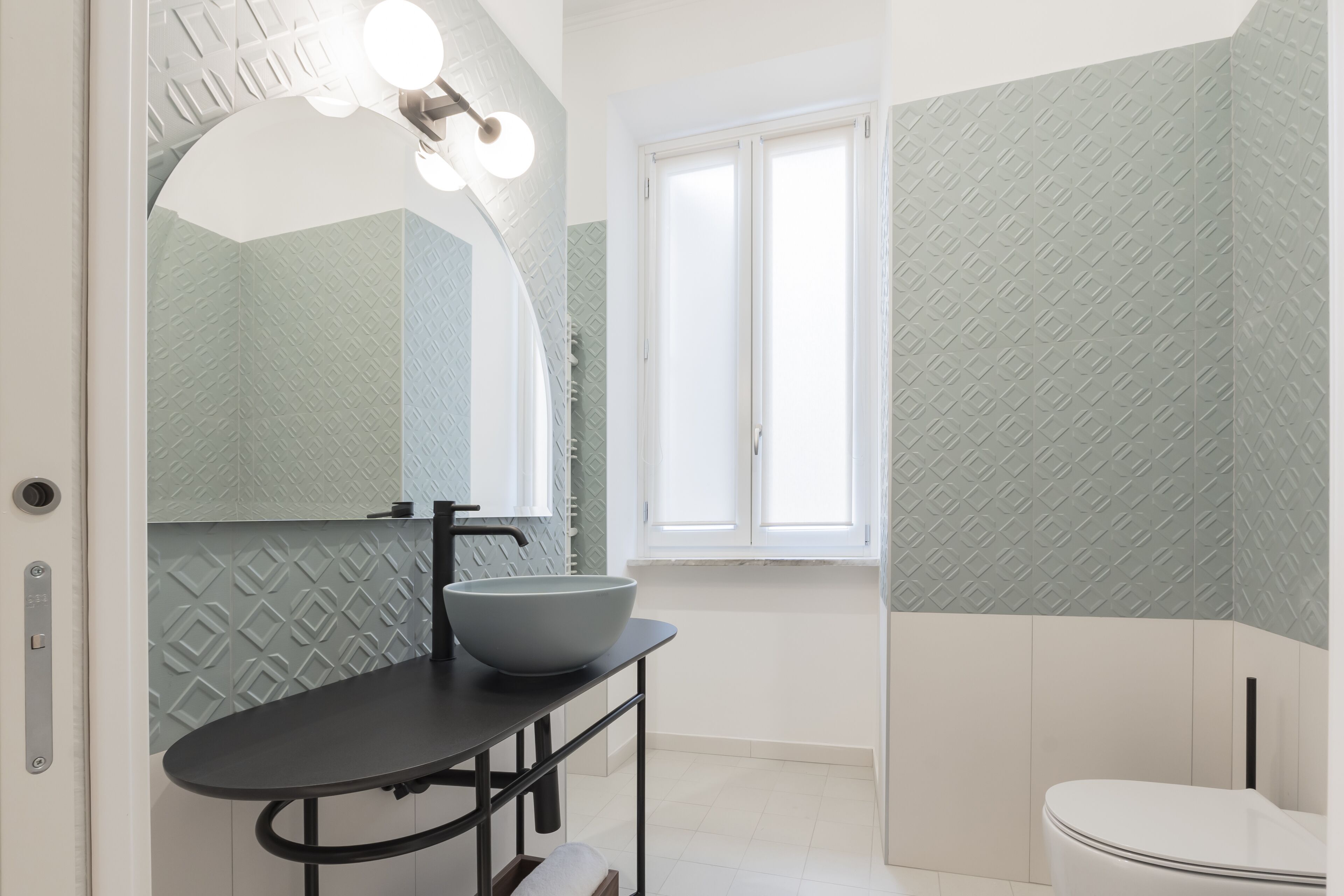 A modern bathroom with a large mirror, a vessel sink, and a toilet.