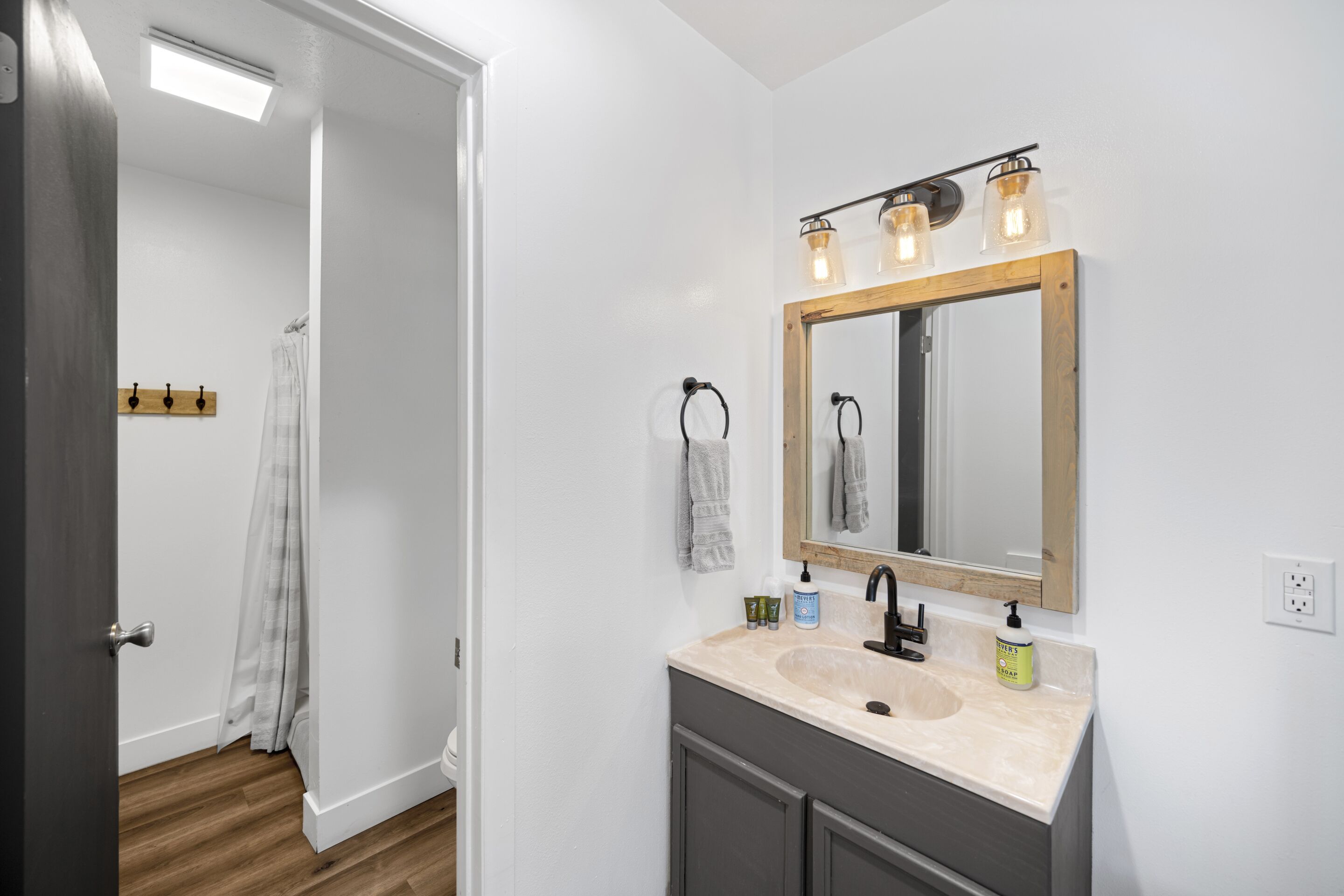 A bathroom with a double sink, a mirror with a wooden frame, and a ceiling light fixture.