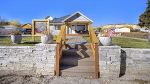 A residential property with a wooden staircase leading to a front porch, a garage, and a well-maintained lawn. - Happy Trails Bed and Breakfast (Tropic)