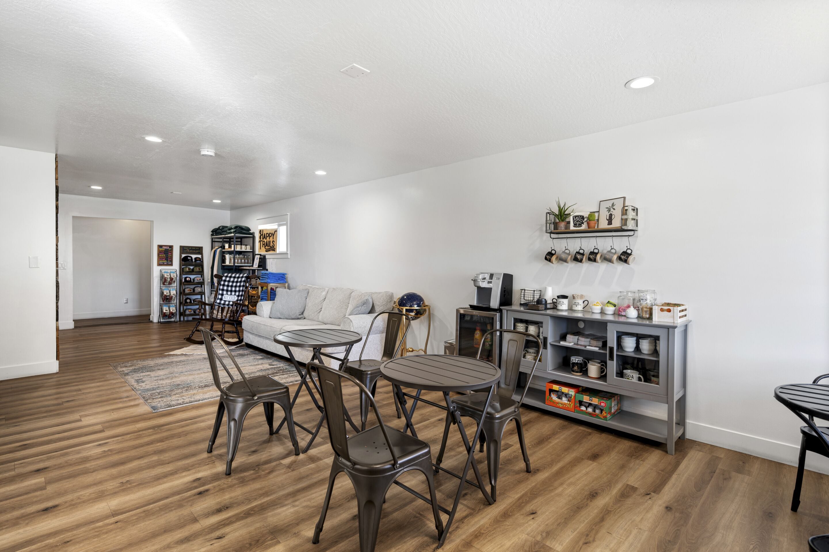 Amplia sala de estar con piso de madera, un sofá, una mesa de centro y un comedor con sillas y una mesa pequeña.