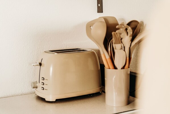 A kitchen counter with a beige toaster and a container holding wooden utensils.