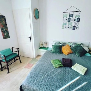 A bedroom with a bed, a chair, a small table, and a wall clock.