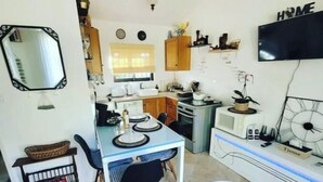 A compact kitchen with a dining area, a TV mounted on the wall, and a small refrigerator. - House in Provence Verte (Cotignac)