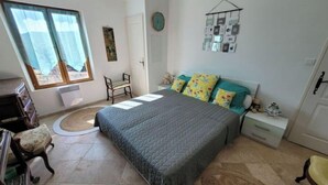 A bedroom with a bed, a chair, a small table, and a window with curtains. - House in Provence Verte (Cotignac)