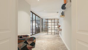 A modern interior with a geometric-patterned sofa, a marble floor, and a minimalist shelving unit. - Be Mate Trastevere II (Rome)