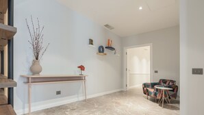 A modern interior with a marble floor, a wooden console table, a vase with branches, and a colorful sofa with a small round table. - Be Mate Trastevere II (Rome)